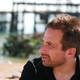 Ken Levine, staring to his left, in front of a blurred seaside pier.